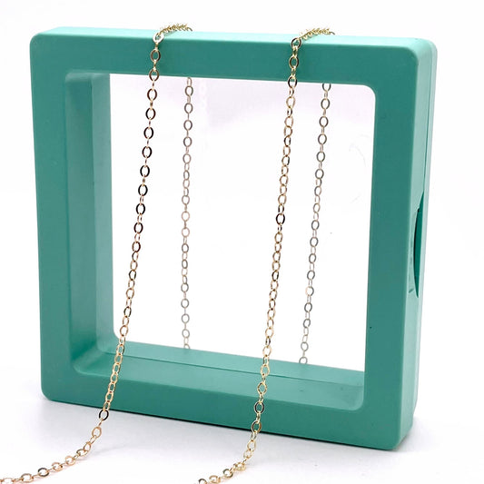  14k Gold Filled 1.68mm Flat Cable chain for permanent jewelry in a green hallow box.